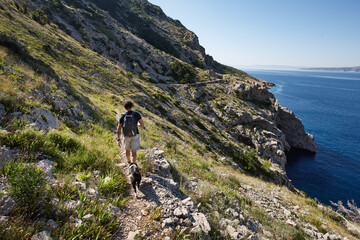 Fototapeta na wymiar Man climbing cliifs with his dog along the sea