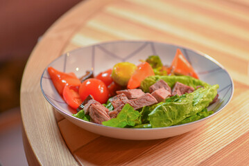 Roasted meat and vegetables salad with tomatoes and brocolli served in a white bowl. Healthy dinner.