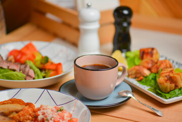 Cup of coffee. Salad with meat and vegetables. Italian cuisine, different dishes served in restaurant.