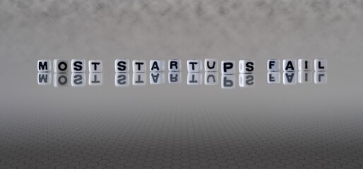 most startups fail concept represented by black and white letter cubes on a grey horizon background stretching to infinity