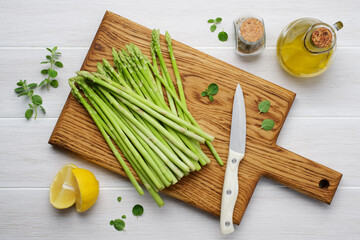 Green asparagus on cutting board. White wood background. Seasonal spring or summer food