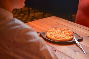 Young woman ready to eat ajarian khachapuri with cheese on wooden board in a restaurant. Still life, eating out concept.