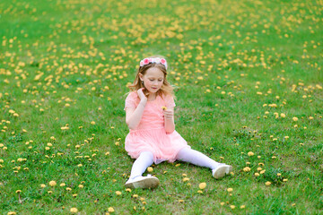 Fototapeta premium Pretty child girl smiling and playing in flowers of the garden, blooming trees, cherry, apples.