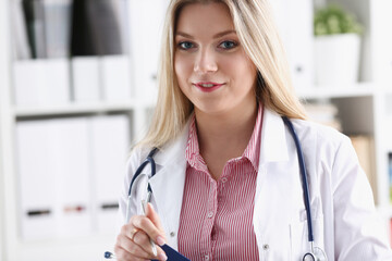 Beautiful smiling female doctor sit at workplace