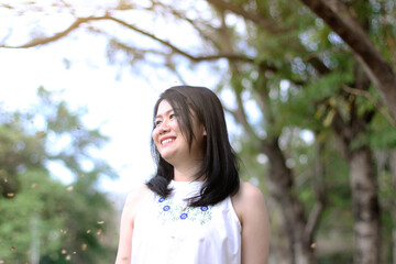 Beautiful asian woman in white dress relax and smiling in nature park. Thai girl or Chinese Girl enjoy on holiday