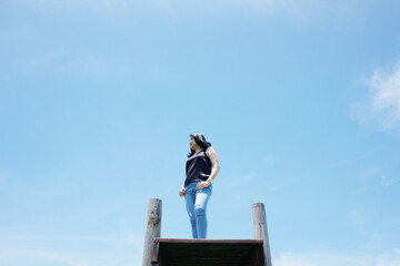Asian woman standing on Wooden bridge is freedom and happy on the blue sky. Happiness of life is successful and travel in the world.