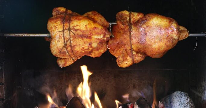 chicken roasting on a spit in garden grill with open fire