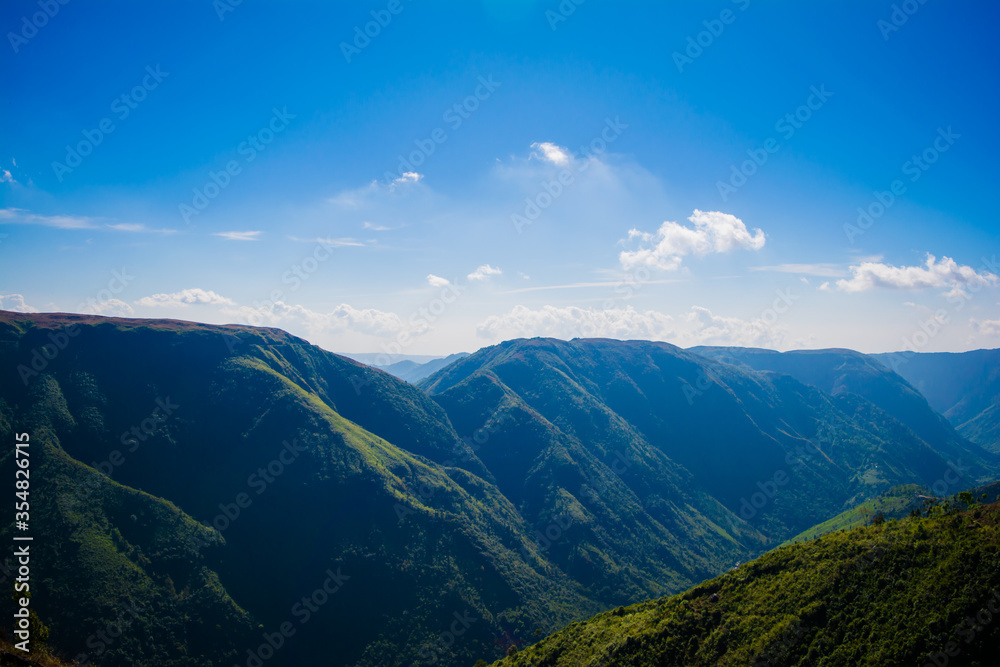 Wall mural Natural view of the folded mountains and lush green valleys with clear sky and clouds of Cherrapunji, Meghalaya, North East India
