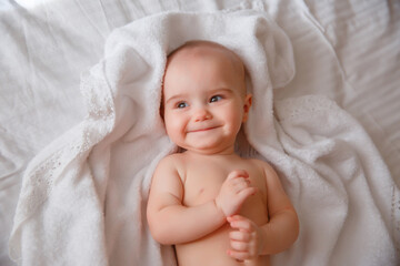 baby in a diaper lying on back  the bed at home smiling, top view