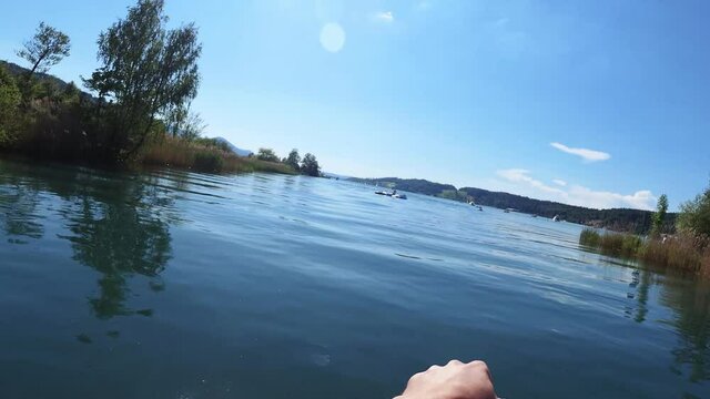 Stand up paddleboarding on the river Linth and lake of Zurich in Switzerland on a clam blue day. POV