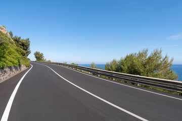 Empty curved coastal road on sunny day