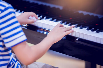 Selective focus to kid fingers and  piano key to play the piano. © Koonsiri