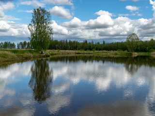 Fototapeta na wymiar calm scene of beautiful sky with cumulus clouds reflection on the lake