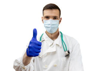 Young doctor with stethoscope in  protective mask and gloves showing thumbs up sign isolated on white background. Focus on hand.