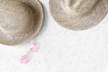 Straw hats for woman and man and pink sunglasses on concrete background.
