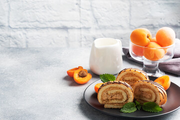Pieces of sweet roll with cream filling on a plate. Fresh apricot berries and mint leaves.