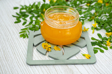 Honey with acacia blossoms on a light wooden background