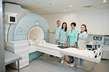 Group of doctors near magnetic resonance imaging machine at hospital.
