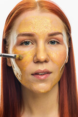 Beauty portrait of red head woman with gold mask on face. Skincare cleansing eco organic cosmetic