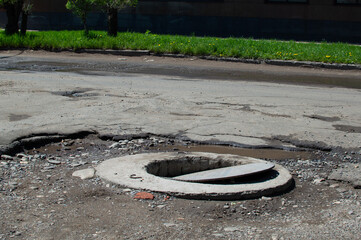 open well on a broken asphalt road