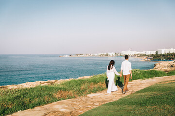 Back view just married couple standing on the rocks in front of the ocean. Just married view from behind. Honeymoon at the sea. High quality photo