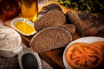 rebanadas de pan de centeno en comida con aceite especias y tomate sobre fondo de madera 