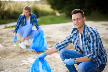 happy volunteers with garbage bags cleaning area in park