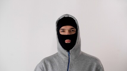 Portrait of a white man in a black balaclava. Thief or criminal is looking at the camera. Face of the criminal world threatens honest citizens. Riots, robbery and marauding.