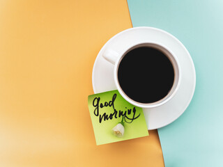 Delicious coffee, flowers and card with GOOD MORNING wish on table, flat lay