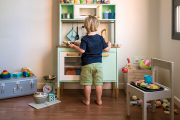 Little blond boys play with a toy kitchen at home during quarantine. Fun at home.