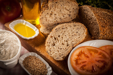 rebanadas de barrita de cereales sobre madera con elementos de decoración tomate aceite semillas rodillo sobre mantel de cuadros