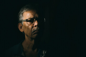 Obraz premium Portrait of a sad Indian Bengali man in light and shadow.