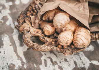 Ginger root on a beautiful wooden tray on an old rustic table. A useful root that has anti-inflammatory effects. Healthy food concept, virus protection,increased immunity during coronavirus quarantine