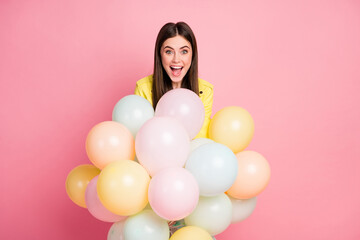 Photo of funny charming lady hold hands many air balloons festive event birthday party open mouth wear trend yellow leather jacket isolated pastel pink color background