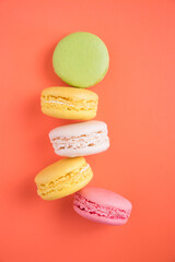 Beautiful bright colorful macaroons on the orange background. Bright background and macaroons.