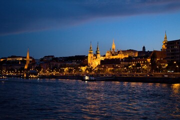 Fototapeta premium Landscape view of Szilágyi Dezső Square Reformed Church and the castle on the Dunabe river in Budapest, Hungary during sundown