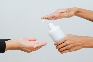 School teacher using alcohol spray or hand sanitizer to student before enter school