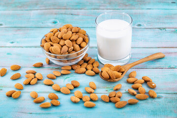 almond nuts in spoon and almond milk in glass on blue wooden table
