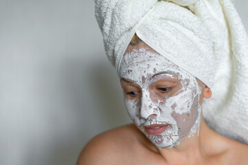 Shy woman on a white background clean face cream on face towel in hair on head. 