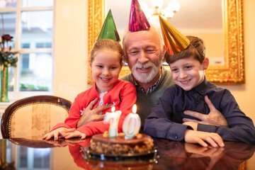 Grandfather and his grandchildren blowing of candles