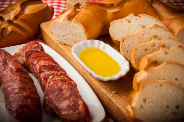 rebanadas rosca de pan de pueblo artesano con decoración chorizo aceite sobre tabla de madera mantel de cuadros