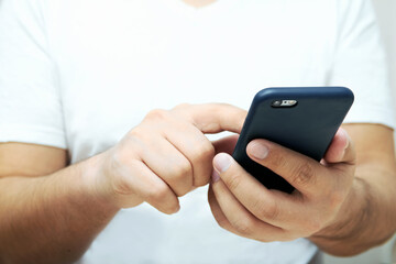 A person is holding a phone and tapping the screen on a white background with copy space. Concept of lifestyle business and Internet technologies in the office