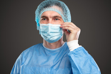Serious doctor adjusting medical mask