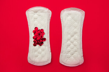 Menstrual pads with bright red glitter on red background. Woman periods cycle, menstruation...
