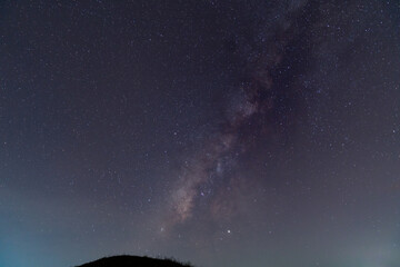 Silhouette of a man with a flashlight, observing beautiful, wide blue night sky with stars and Milky way galaxy. Astronomy, orientation, clear sky concept and background.