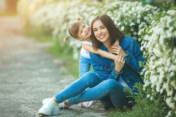 Attractive young mother holding her little daughter. Girls outdoors having fun together.