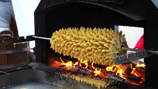 Cooking traditional culinary heritage layered spit cake - sakotis, baumkuchen in outdoor oven, Vilnius Lithuania