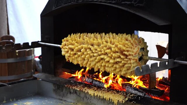 Cooking traditional culinary heritage layered spit cake - sakotis, baumkuchen in outdoor oven, Vilnius Lithuania, slow motion