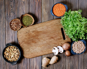 Legumes, lentils, chickpea and beans assortment top view. Composition of different types of legumes in bowls on wooden background for healthy nutrition. Copy space.