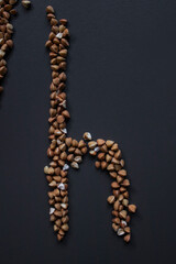 Letter 'L' written with buckwheat On gray background, top view, copy space. Food supplies crisis, food donation on quarantine isolation period